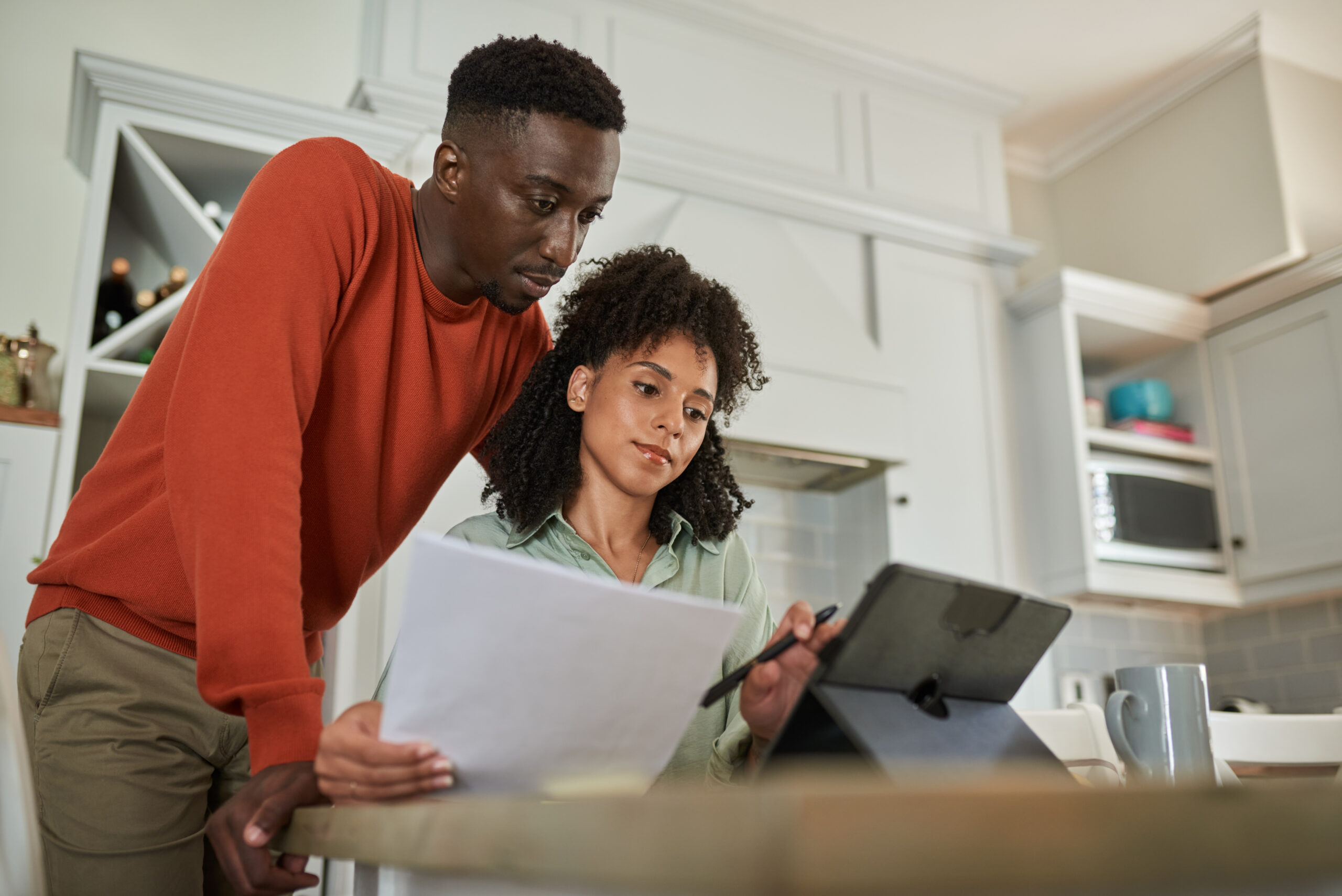 Young multiracial couple paying their bills while doing their online banking on a digital tablet at home